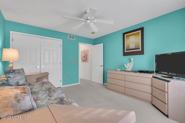 bedroom with ceiling fan, light colored carpet, a closet, and a textured ceiling