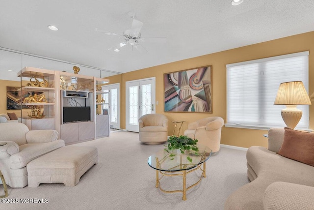 living room featuring french doors, ceiling fan, carpet, and a textured ceiling