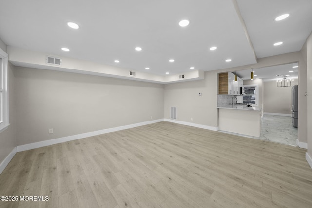 unfurnished living room featuring sink and light wood-type flooring