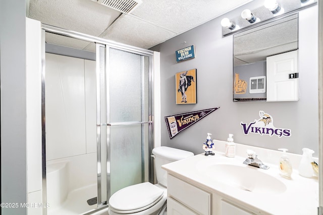 bathroom featuring vanity, toilet, an enclosed shower, and a drop ceiling