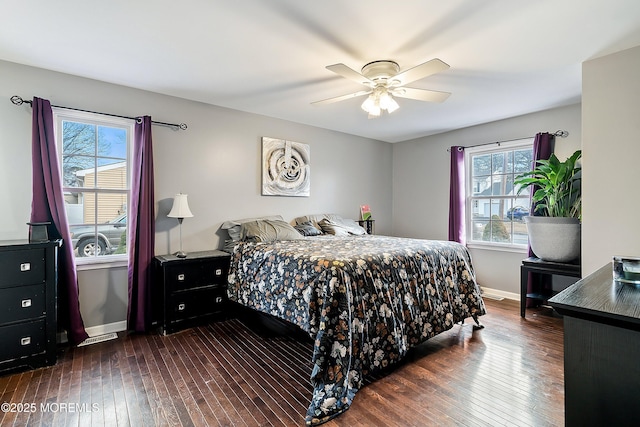 bedroom featuring ceiling fan, dark hardwood / wood-style flooring, and multiple windows