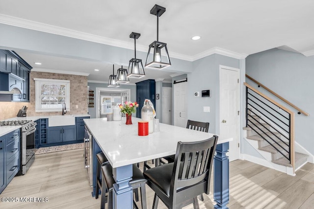 dining area with crown molding, light hardwood / wood-style flooring, sink, and a barn door