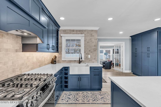 kitchen with sink, blue cabinetry, crown molding, gas range, and tasteful backsplash