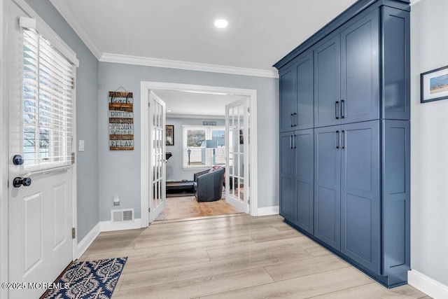 entryway with ornamental molding, light wood-type flooring, and french doors