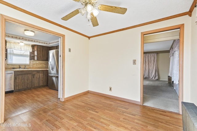 empty room with ceiling fan, ornamental molding, sink, and light wood-type flooring