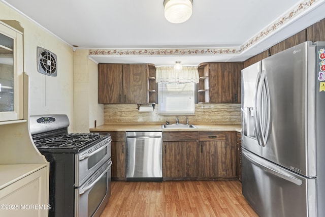 kitchen featuring appliances with stainless steel finishes, sink, backsplash, light hardwood / wood-style floors, and dark brown cabinets