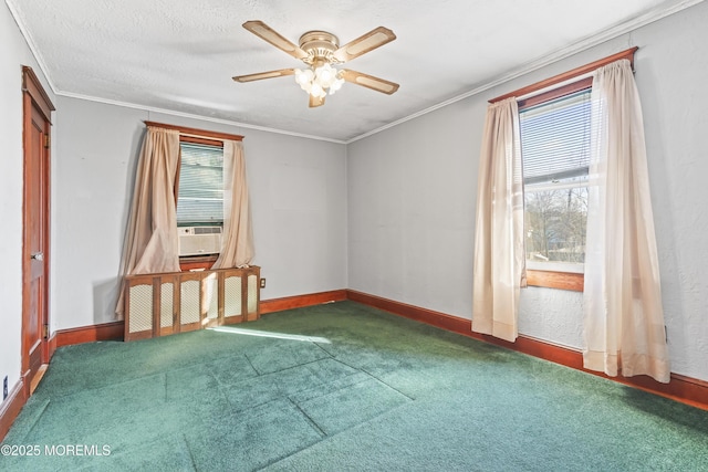 carpeted spare room featuring ceiling fan, ornamental molding, and plenty of natural light