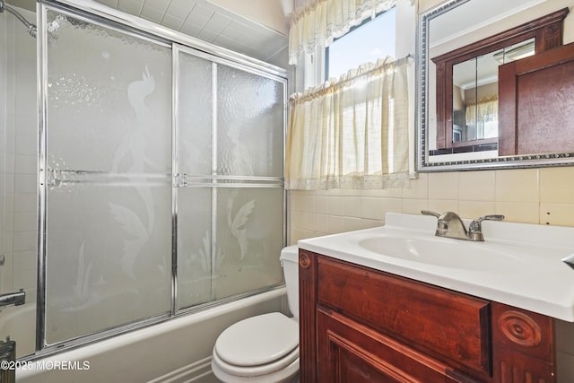 full bathroom with bath / shower combo with glass door, tile walls, decorative backsplash, vanity, and toilet