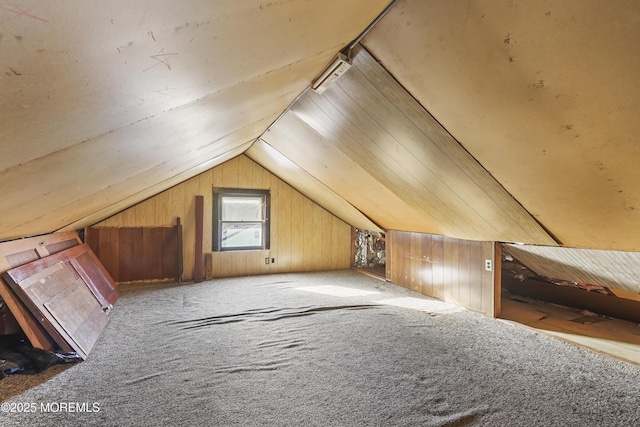 bonus room featuring lofted ceiling, carpet flooring, and wooden walls