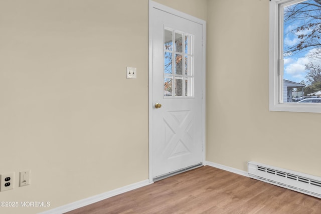 doorway to outside featuring a baseboard heating unit and light wood-type flooring