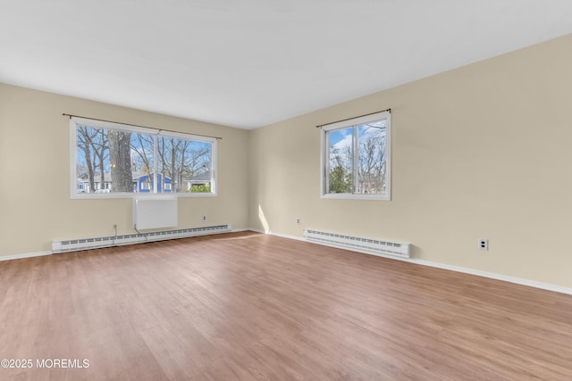 empty room featuring a baseboard heating unit and light hardwood / wood-style flooring