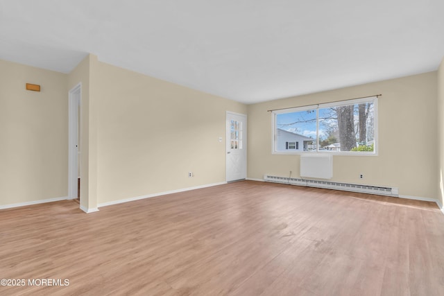 spare room featuring baseboard heating and light hardwood / wood-style flooring