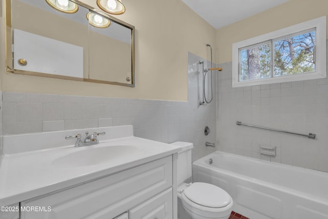 full bathroom featuring tiled shower / bath, vanity, toilet, and tile walls