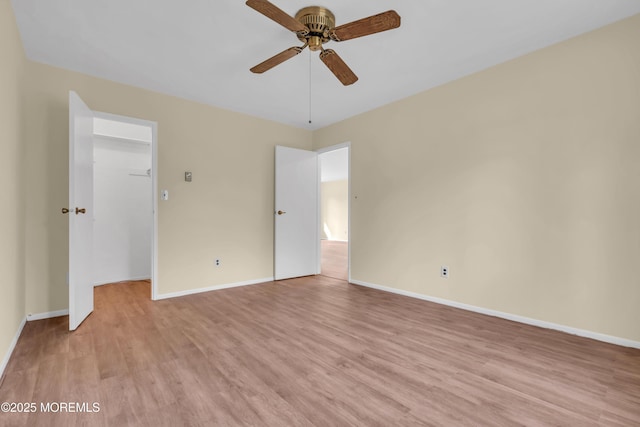 unfurnished bedroom with a walk in closet, light hardwood / wood-style floors, a closet, and ceiling fan