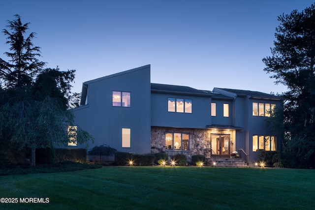 back house at dusk with a lawn