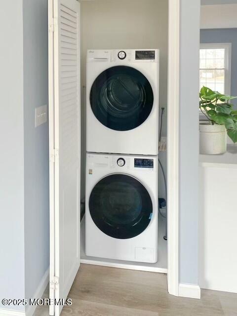 laundry room featuring stacked washer and clothes dryer and light hardwood / wood-style floors