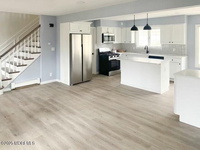 kitchen with a center island, hanging light fixtures, baseboard heating, stainless steel appliances, and white cabinets