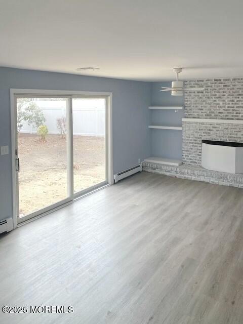 unfurnished living room with ceiling fan, a baseboard radiator, a fireplace, and hardwood / wood-style floors