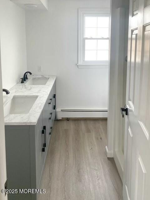 bathroom with wood-type flooring, vanity, and baseboard heating