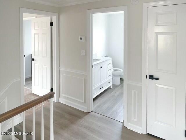 hall with ornamental molding and light hardwood / wood-style floors