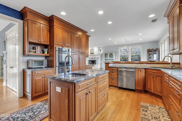 kitchen with a sink, dark stone countertops, appliances with stainless steel finishes, pendant lighting, and a center island