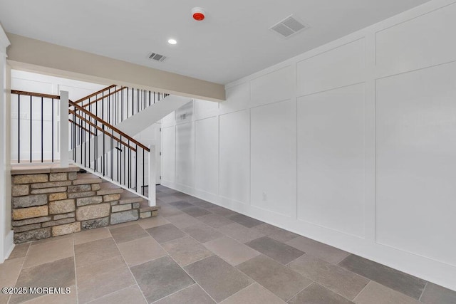 basement featuring recessed lighting, a decorative wall, stairs, and visible vents