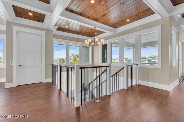 hallway featuring plenty of natural light, coffered ceiling, a notable chandelier, and an upstairs landing