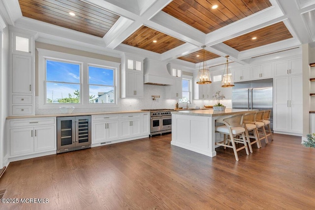 kitchen with custom range hood, coffered ceiling, beverage cooler, and high quality appliances