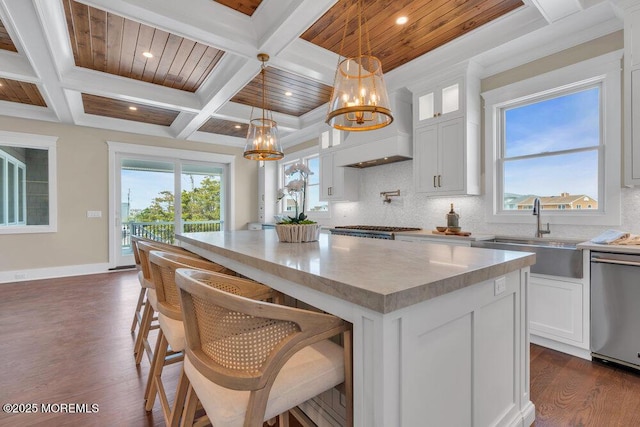 kitchen featuring a notable chandelier, a sink, dishwasher, a center island, and coffered ceiling