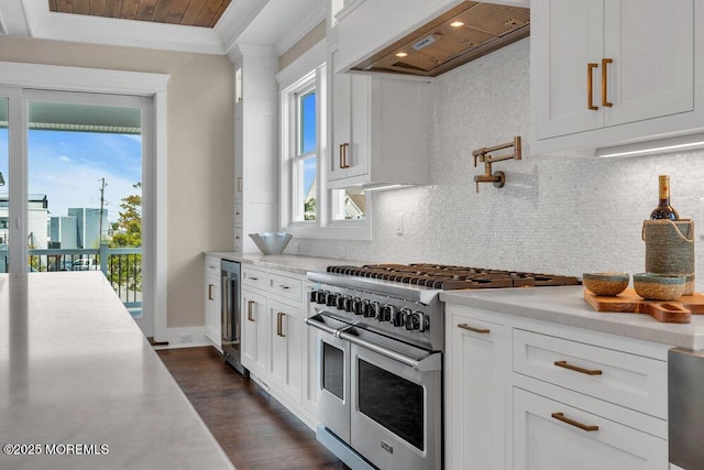 kitchen with backsplash, range with two ovens, beverage cooler, and premium range hood
