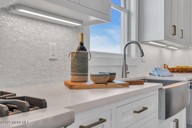details featuring light countertops, white cabinets, a sink, and tasteful backsplash