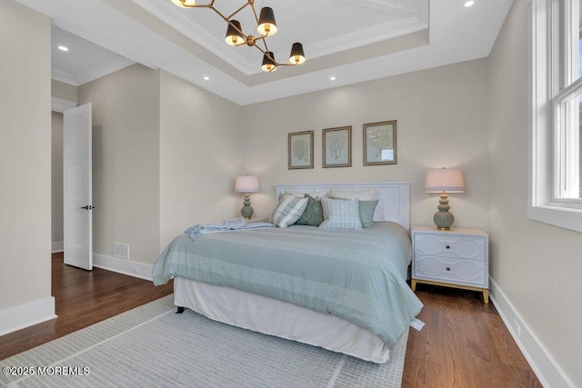 bedroom featuring a chandelier, baseboards, wood finished floors, a tray ceiling, and ornamental molding