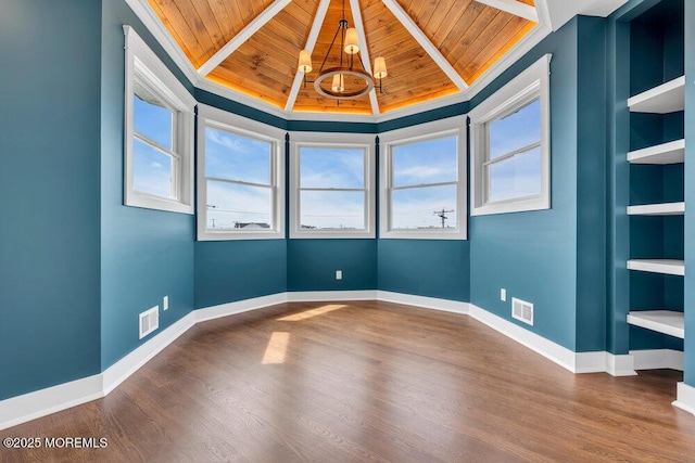 empty room featuring a notable chandelier, visible vents, wooden ceiling, and wood finished floors