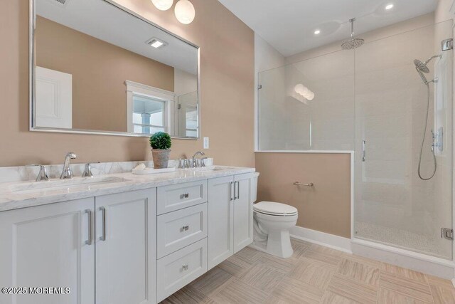 bathroom featuring double vanity, toilet, a sink, and a stall shower