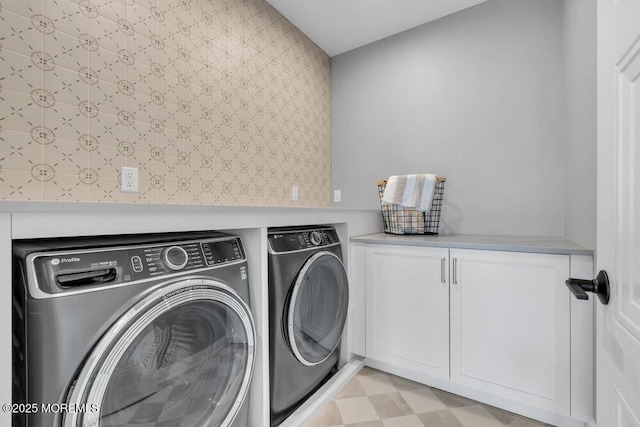 washroom featuring washing machine and clothes dryer, light floors, and cabinet space