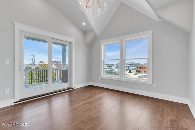 unfurnished room with a healthy amount of sunlight, lofted ceiling, dark wood finished floors, and a chandelier