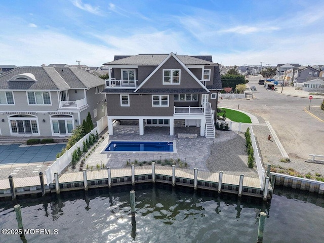 rear view of house with a residential view, stairs, a fenced backyard, a fenced in pool, and a water view