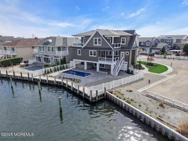 rear view of house with a residential view, a jacuzzi, a water view, and a balcony