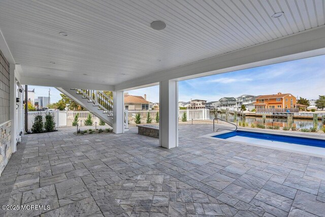 view of patio / terrace featuring a residential view, stairs, a fenced backyard, a fenced in pool, and a water view