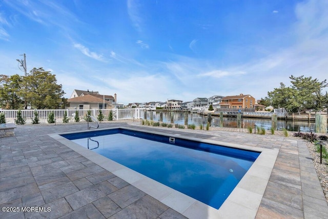 view of swimming pool featuring fence, a fenced in pool, a water view, and a patio area