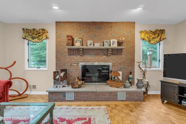 living room featuring light parquet flooring, plenty of natural light, and a brick fireplace