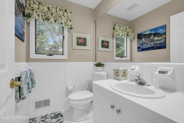 bathroom with vanity, plenty of natural light, tile walls, and toilet