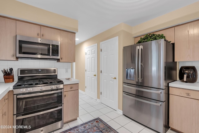 kitchen featuring light tile patterned flooring, appliances with stainless steel finishes, light brown cabinets, and backsplash