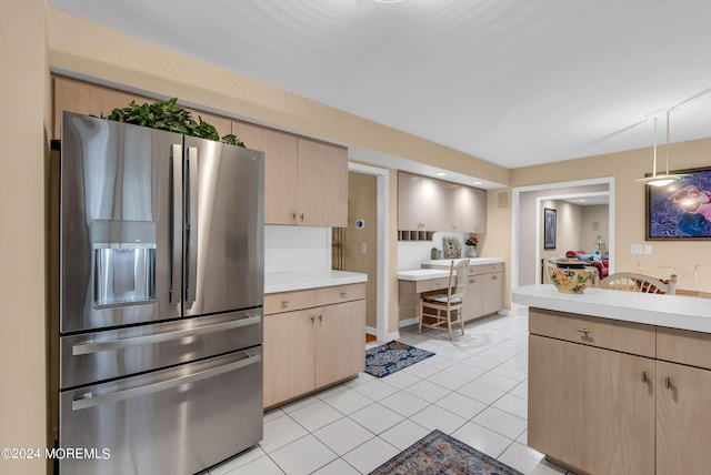 kitchen featuring light brown cabinetry, decorative backsplash, hanging light fixtures, light tile patterned floors, and stainless steel refrigerator with ice dispenser