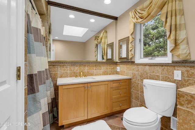 bathroom featuring tile walls, tile patterned flooring, a skylight, vanity, and toilet