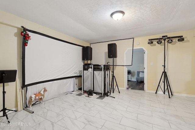 basement with baseboards, arched walkways, and a textured ceiling