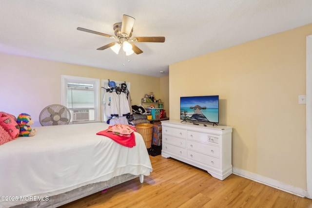 bedroom with light wood-style floors, cooling unit, baseboards, and a ceiling fan