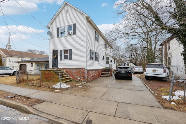 view of property exterior with brick siding, driveway, and fence