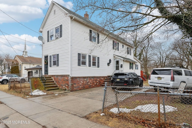view of side of property with brick siding, a fenced front yard, and a chimney