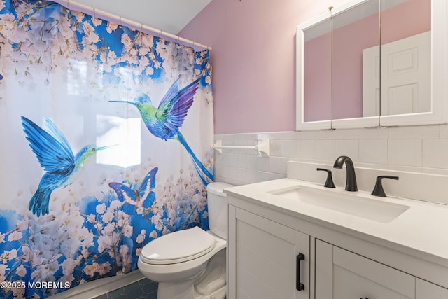 bathroom featuring vanity, toilet, and tile walls